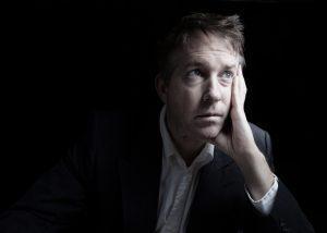 Portrait of businessman looking hopeless while working late at night on black background with copy space